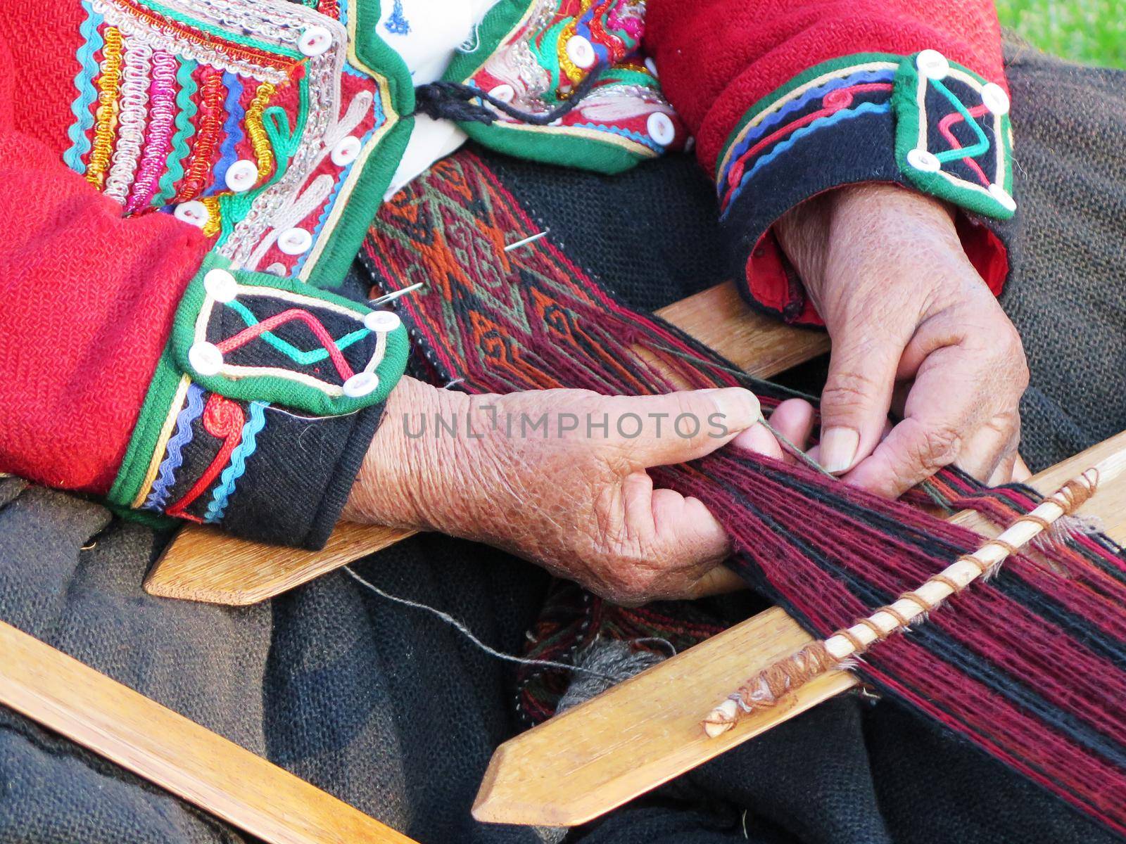 Close up of Peruvian lady in authentic dress spinning yarn by hand by aroas