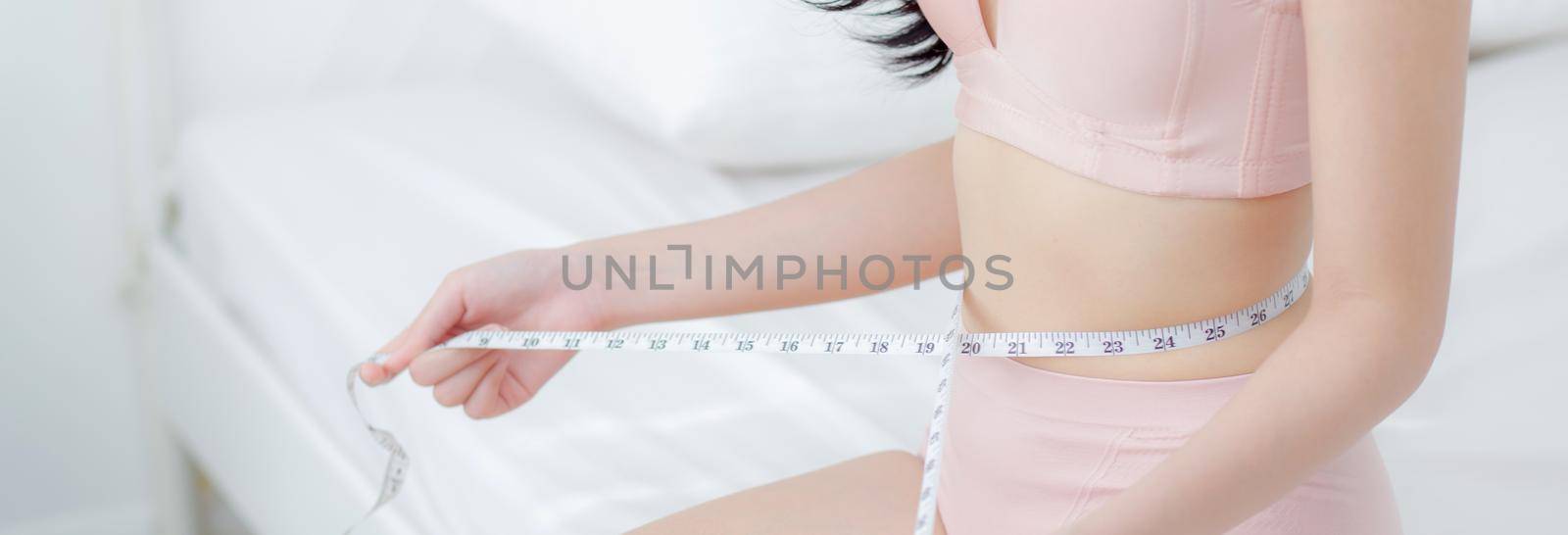 Beautiful young asian woman sexy body slim measuring abdomen for control weight loss in the room, beauty girl belly thin have cellulite with tape measure for diet, health concept, banner website.