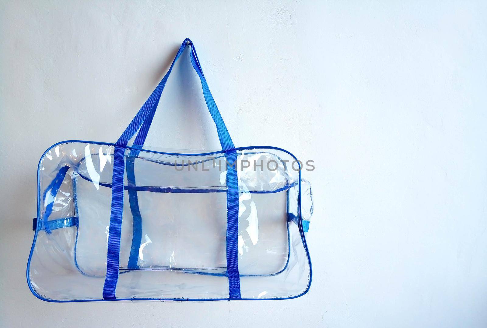 Plastic bag with blue handles hanging on a nail, on a white background by lapushka62