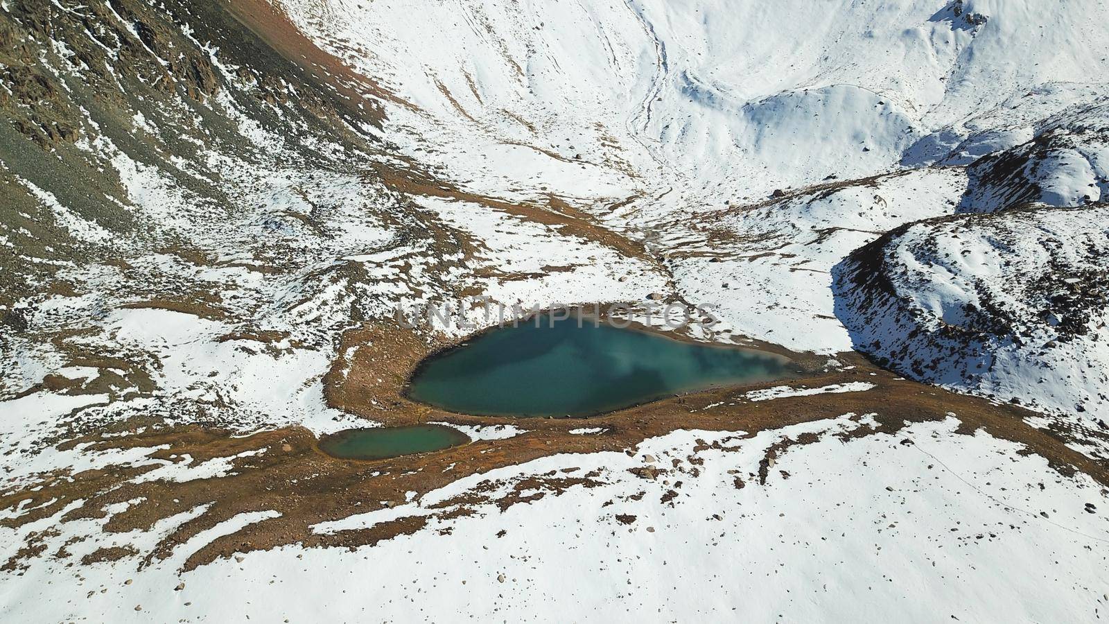 Snow-capped mountains and a lake. View from top. by Passcal