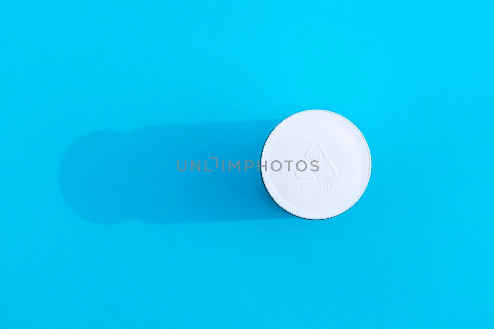 a bottle with a white cap with a recycling sign with a hard shadow on a colorful background. High quality photo