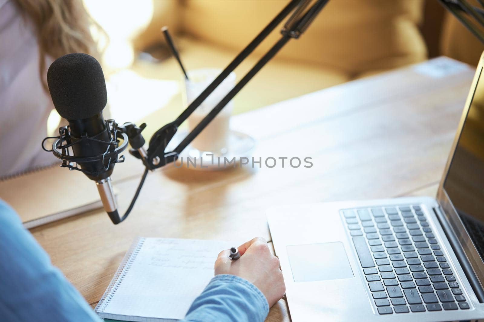 Woman writing information near laptop and microphone.  by SerhiiBobyk