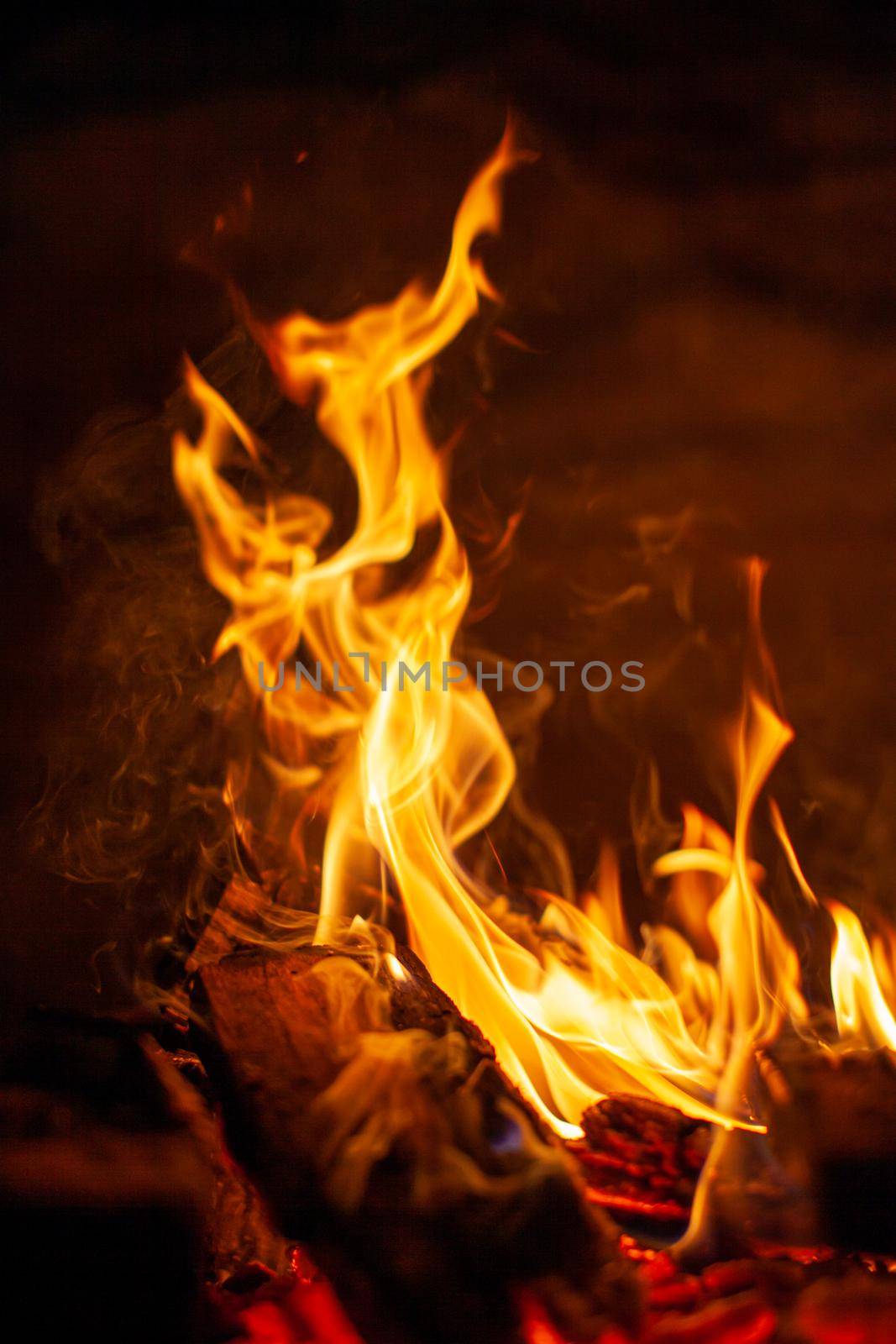 A campfire burns in the snow at night in the snow in the cold winter. The flame of the fire warms and illuminates. Flame, background