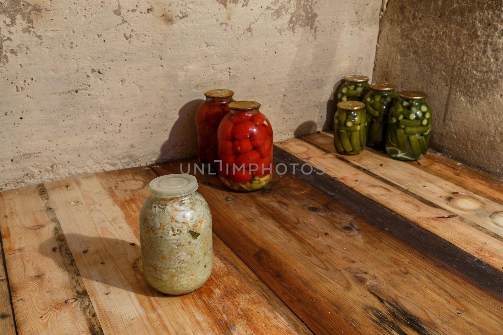 basement with few pickled vegetables in glass jars on wooden planks shelf