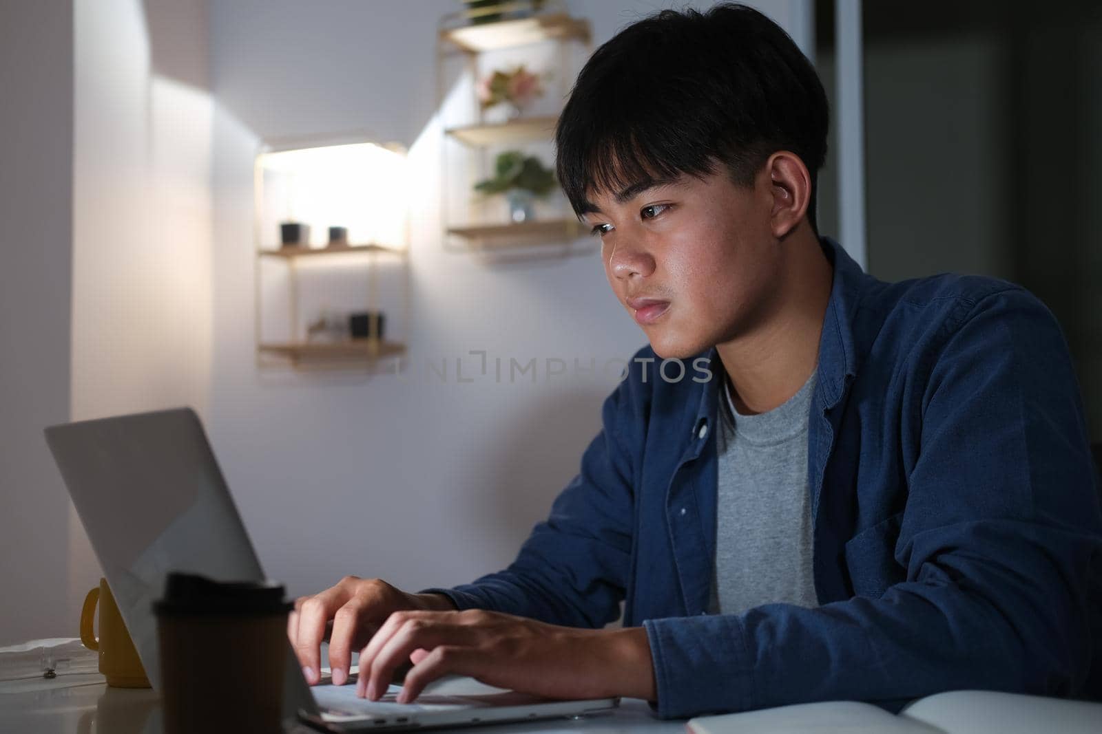 Young collage man learning online at night at his home. 
