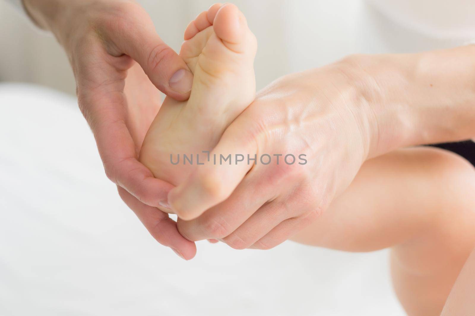 Mom gives her baby a leg and foot massage. Close-up. A satisfied baby lies on the massage table.