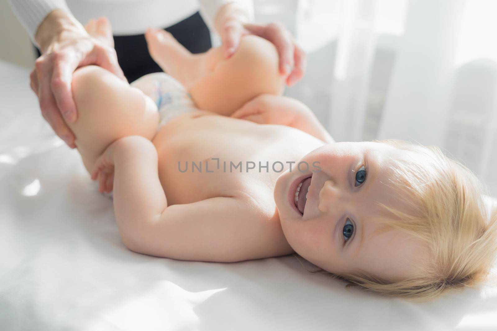 Mom does baby gymnastics for the baby's legs. Close-up. by Yurich32