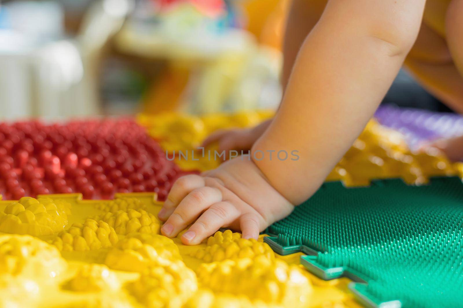 The kid walks barefoot on multi-colored massage rugs. Foot massage