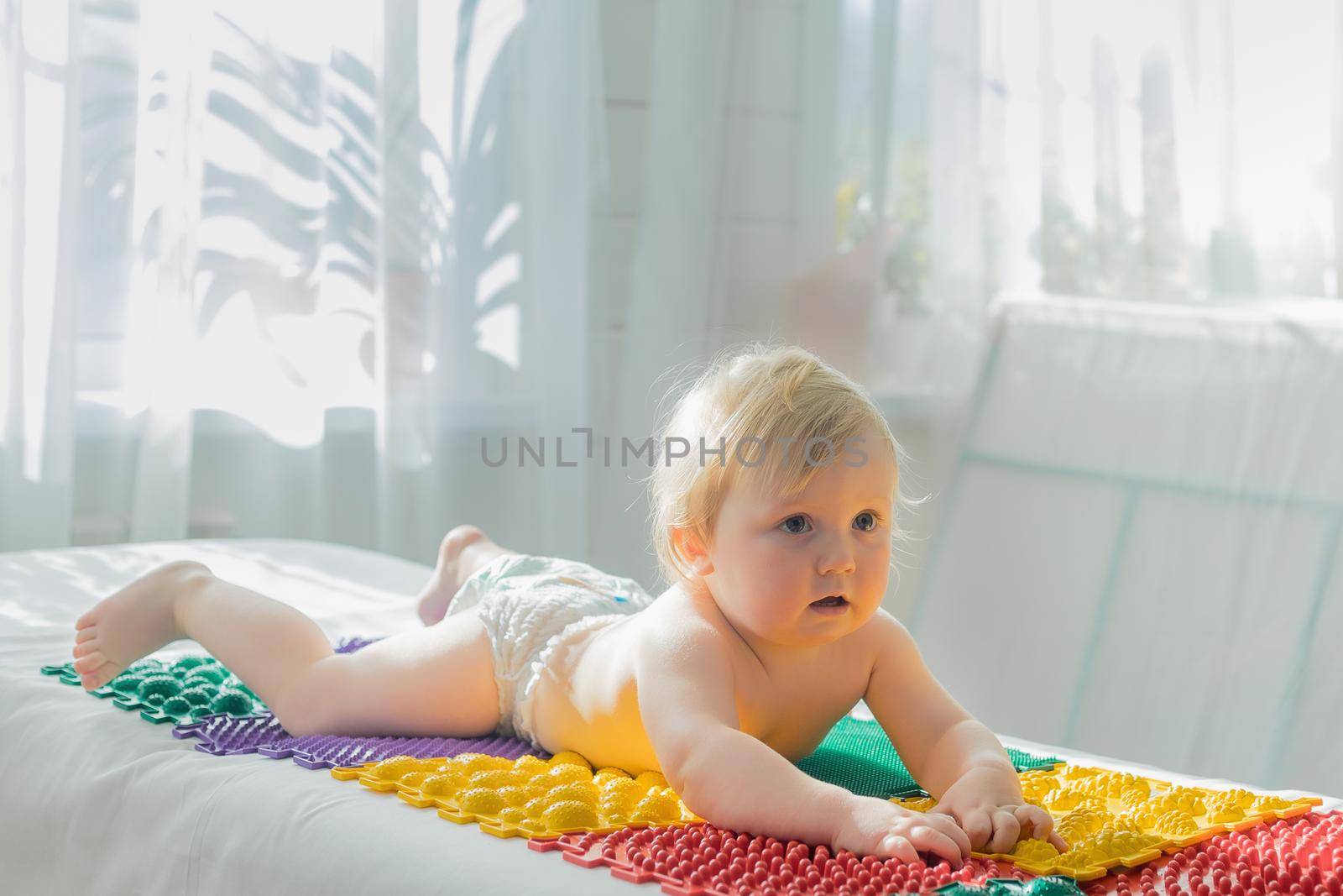 The baby lies on the massage mats with his stomach down. Close-up.