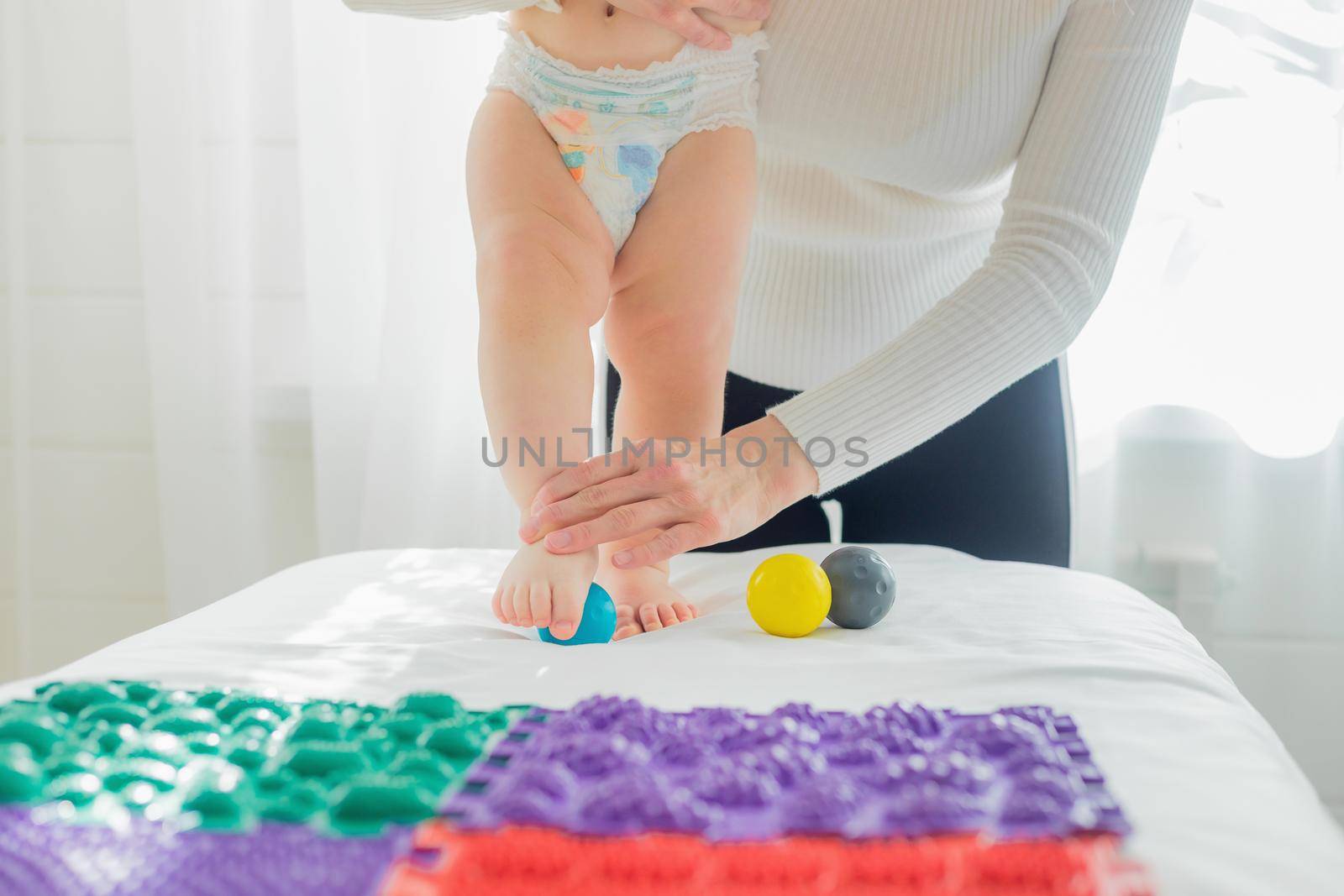 Mom gives the baby a foot massage with massage balls. by Yurich32