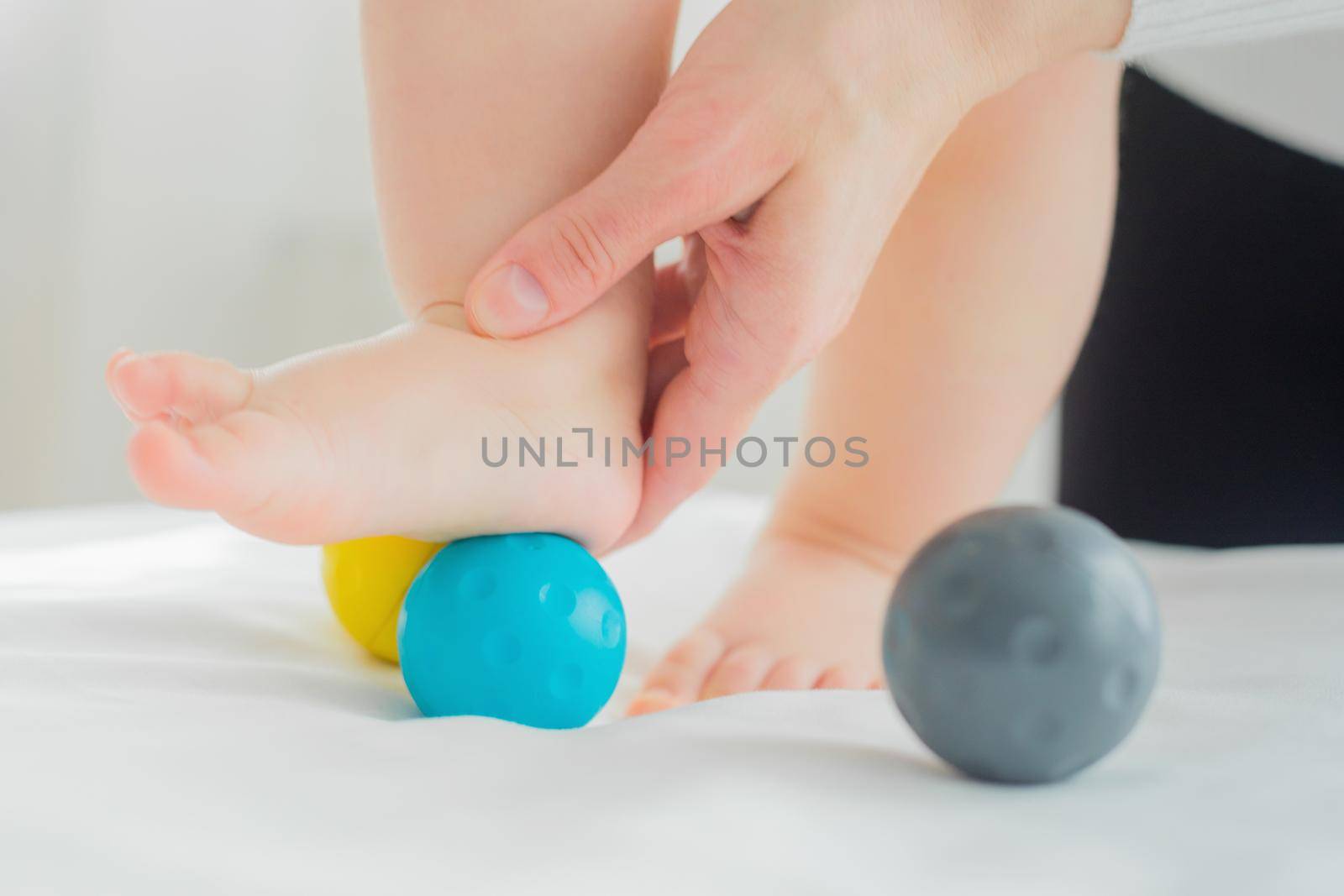 Mom gives the baby a foot massage with massage balls. Close-up