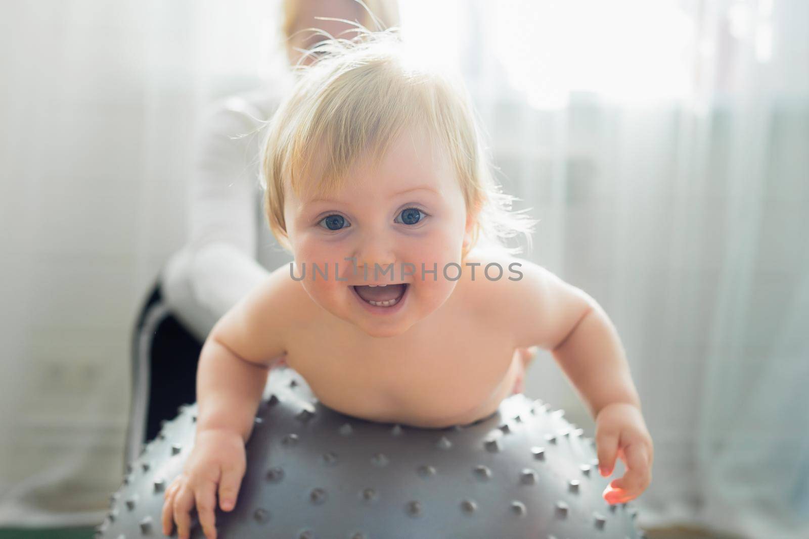 Mom is engaged in gymnastics with the baby on an inflatable ball. Fitball, gymnastics for a child.