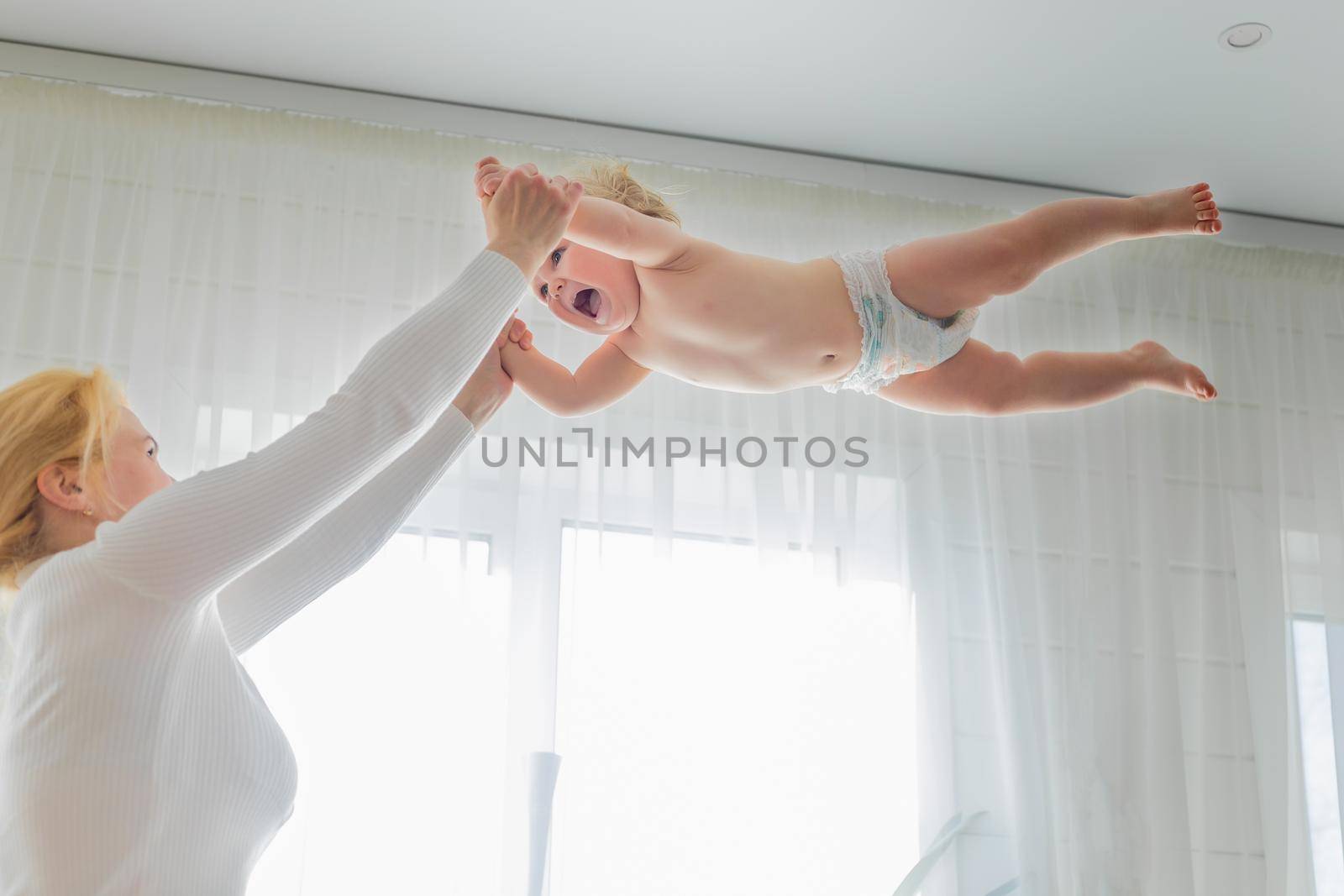 Mom, entertaining the baby, throws him up, rejoicing and having fun.