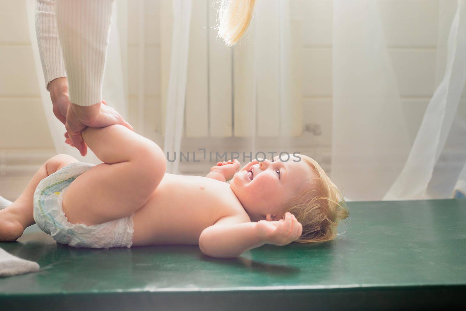 Mom does baby gymnastics for the baby's legs. Close-up. by Yurich32