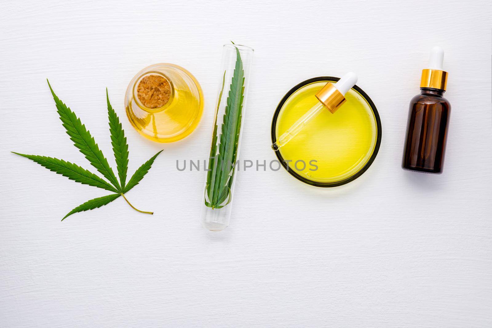 Glass bottle of cannabis oil and hemp leaves set up  on white background. by kerdkanno