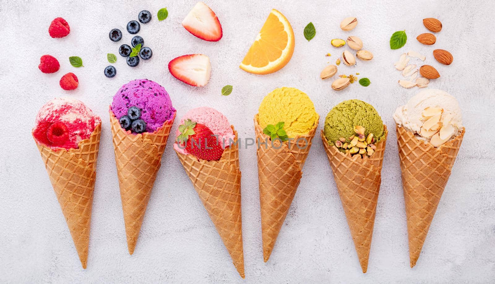Various of ice cream flavor in cones blueberry ,pistachio ,almond ,orange and cherry setup on white stone background . Summer and Sweet menu concept.  by kerdkanno