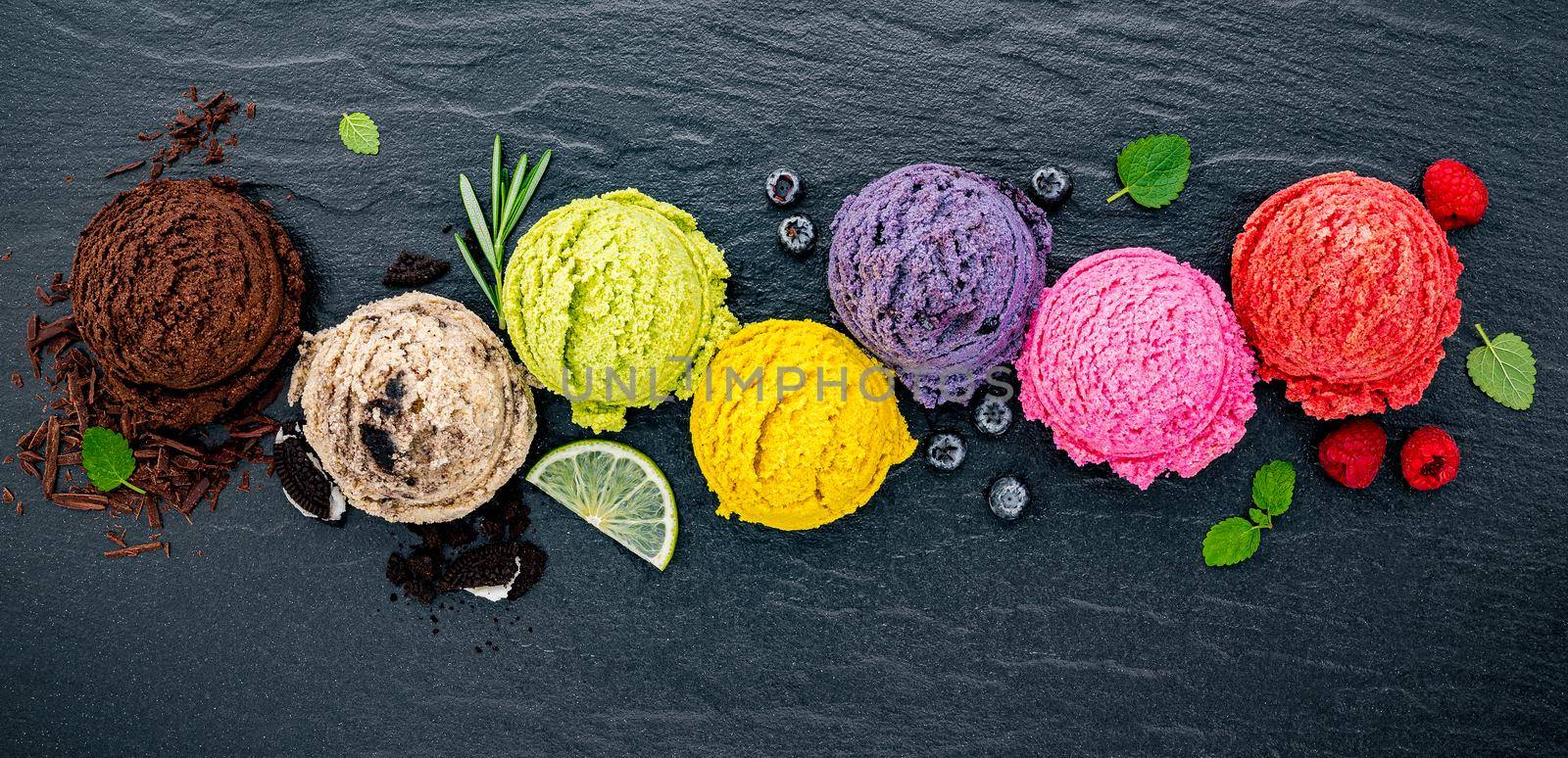 Various of ice cream flavor ball blueberry ,lime ,pistachio ,almond ,orange ,chocolate and vanilla set up on dark stone background . Summer and Sweet menu concept. by kerdkanno