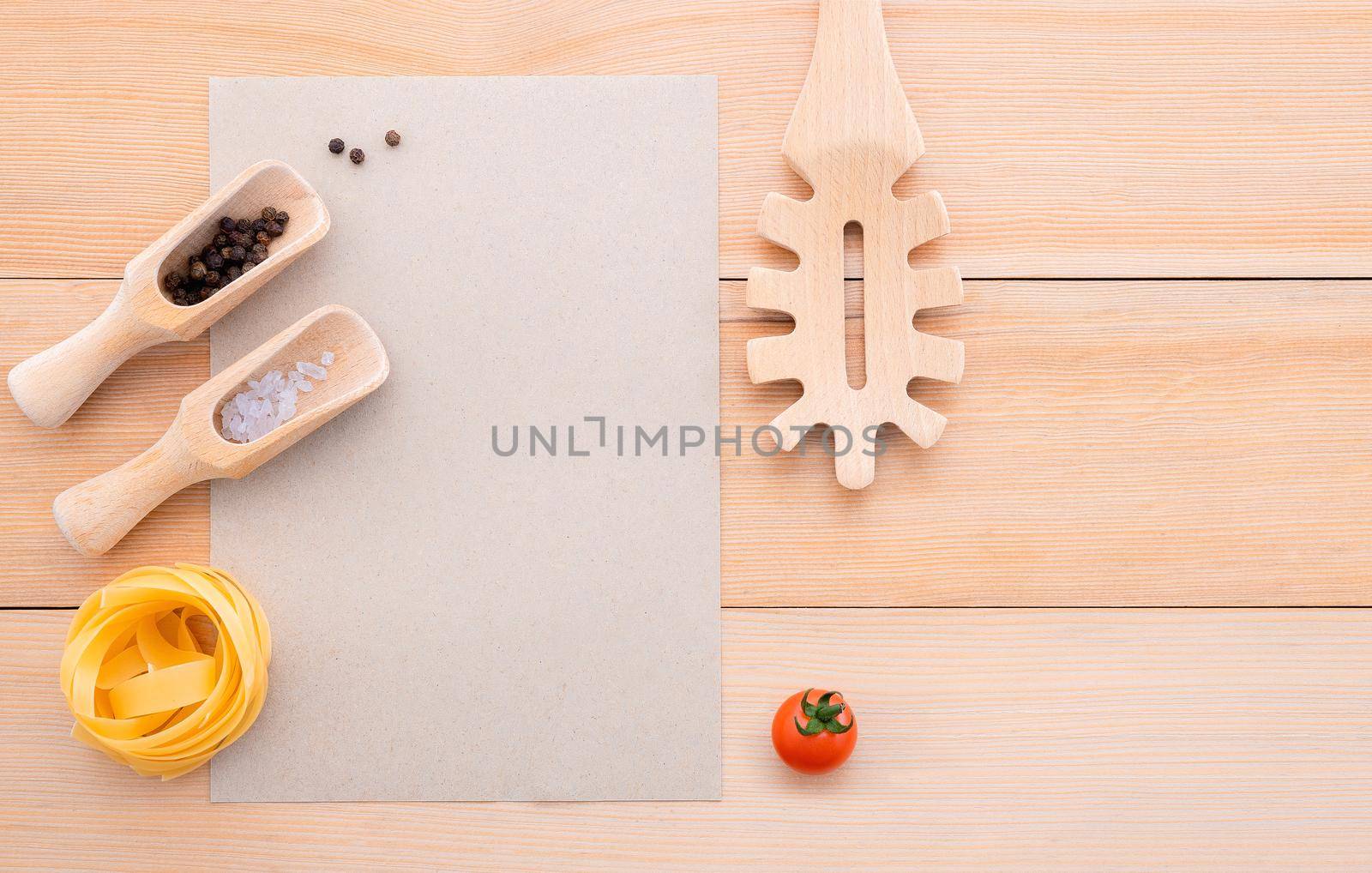 Food background for tasty Italian dishes with blank brown paper and vintage pasta ladle on wooden background. Top view italian foods concept and menu design with copy space.