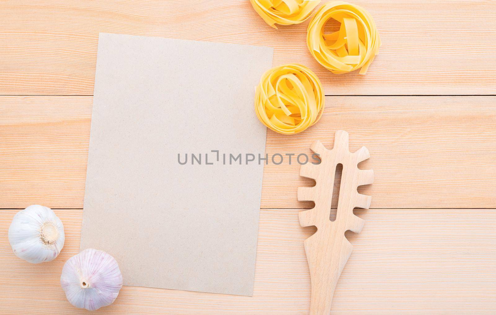 Italian foods concept and menu design . Blank paper and  pasta ladle on wooden background.Food background for tasty Italian dishes with blank brown paper and vintage pasta ladle on wooden background. Top view italian foods concept and menu design with copy space. by kerdkanno