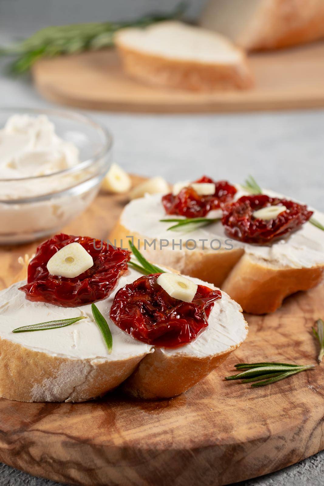 Homemade sandwiches with cream cheese and sun-dried tomatoes on a wooden board of olive - delicious healthy breakfast, italian cuisine, vertical image, copy space.