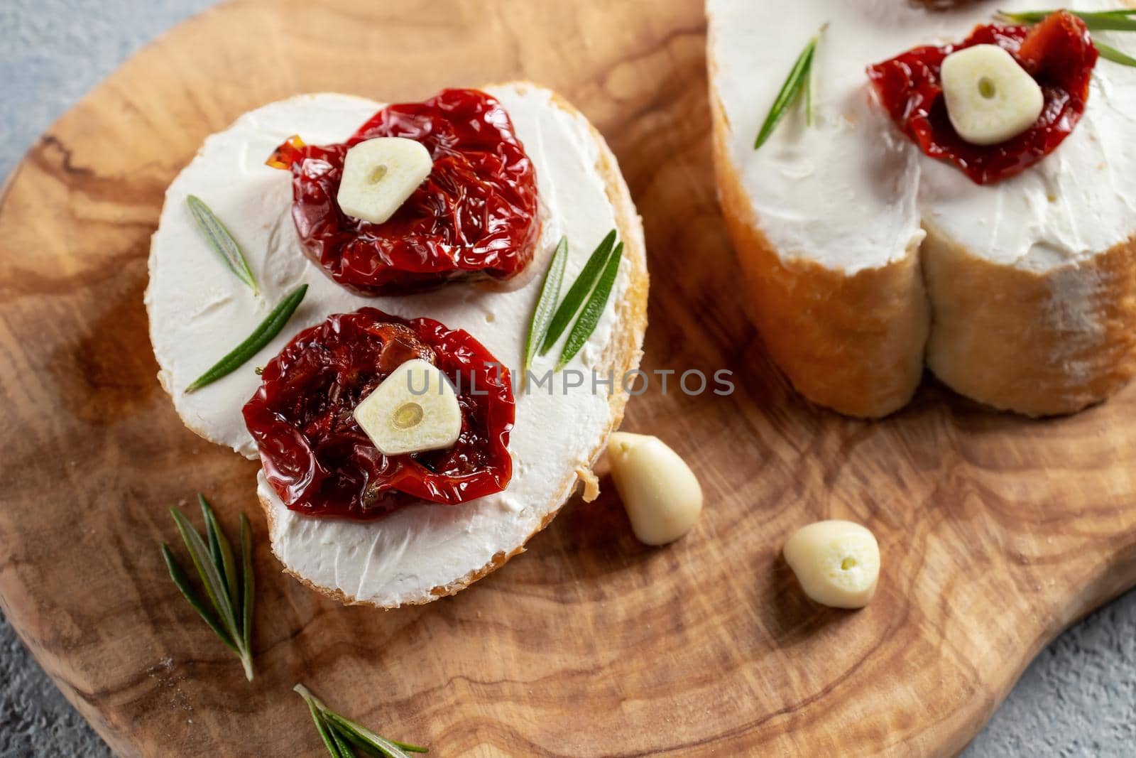 Homemade sandwiches with cream cheese and sun-dried tomatoes on a wooden board of olive - delicious healthy breakfast, italian cuisine.