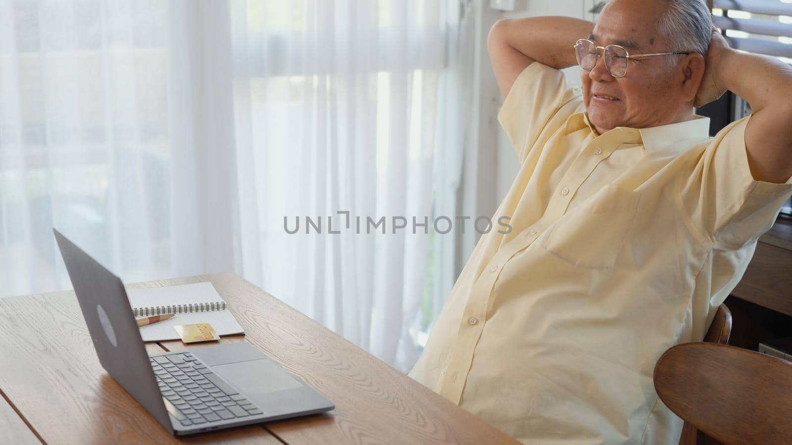 Senior man dressed wear eyeglasses sitting on chair working on laptop in living room at home, Happy old man retired using computer, Elderly grandfather work from home