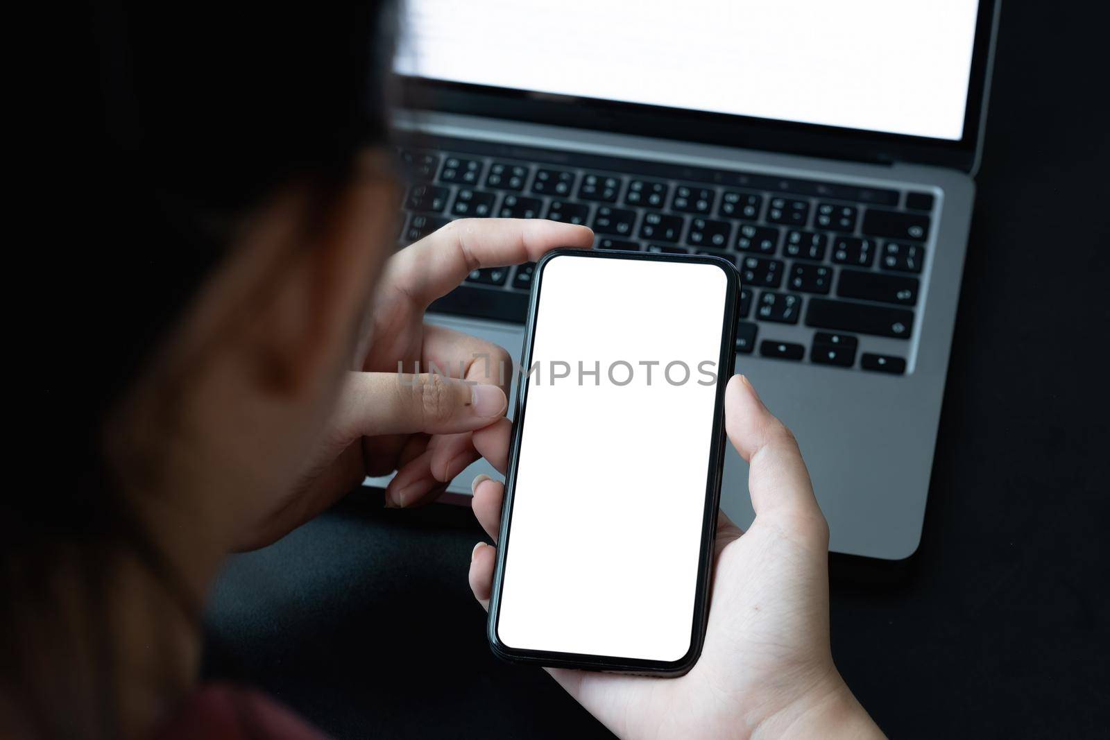 Top view of businesswoman using smartphone on workplcae with blank white screen. mock up mobile phone