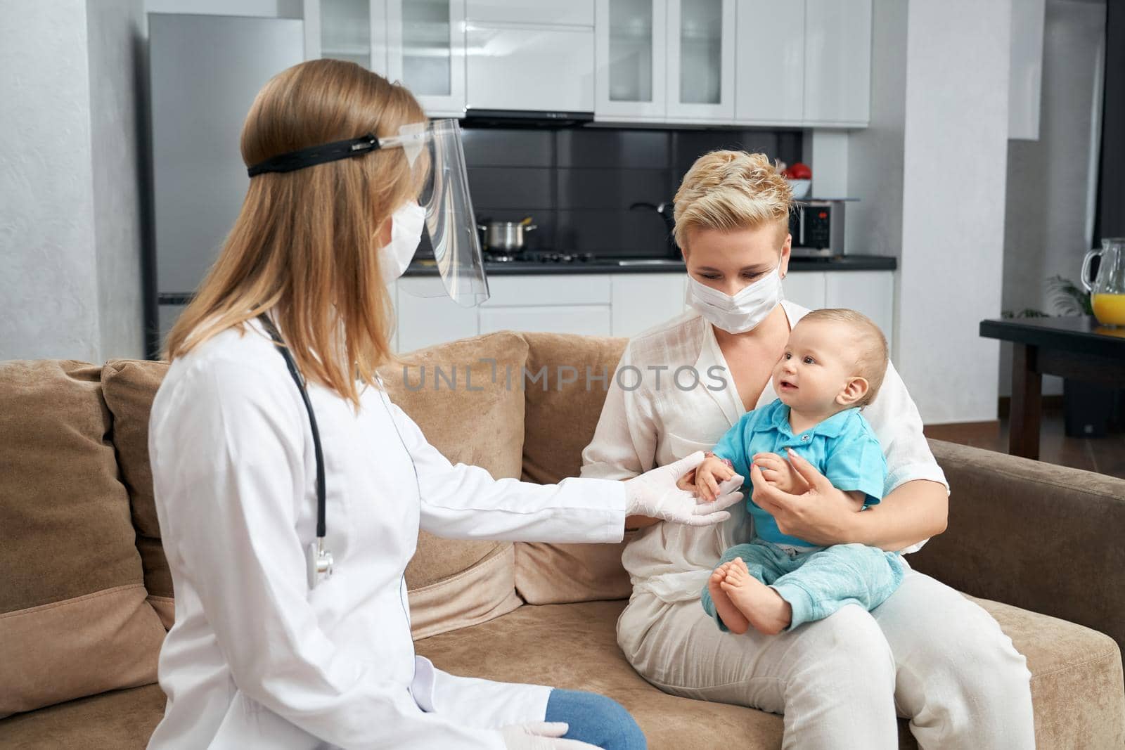 Pretty mother holding her son while doctor sitting near by SerhiiBobyk