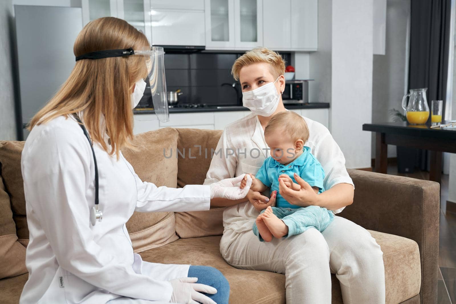 Competent doctor in mask examining baby at home by SerhiiBobyk