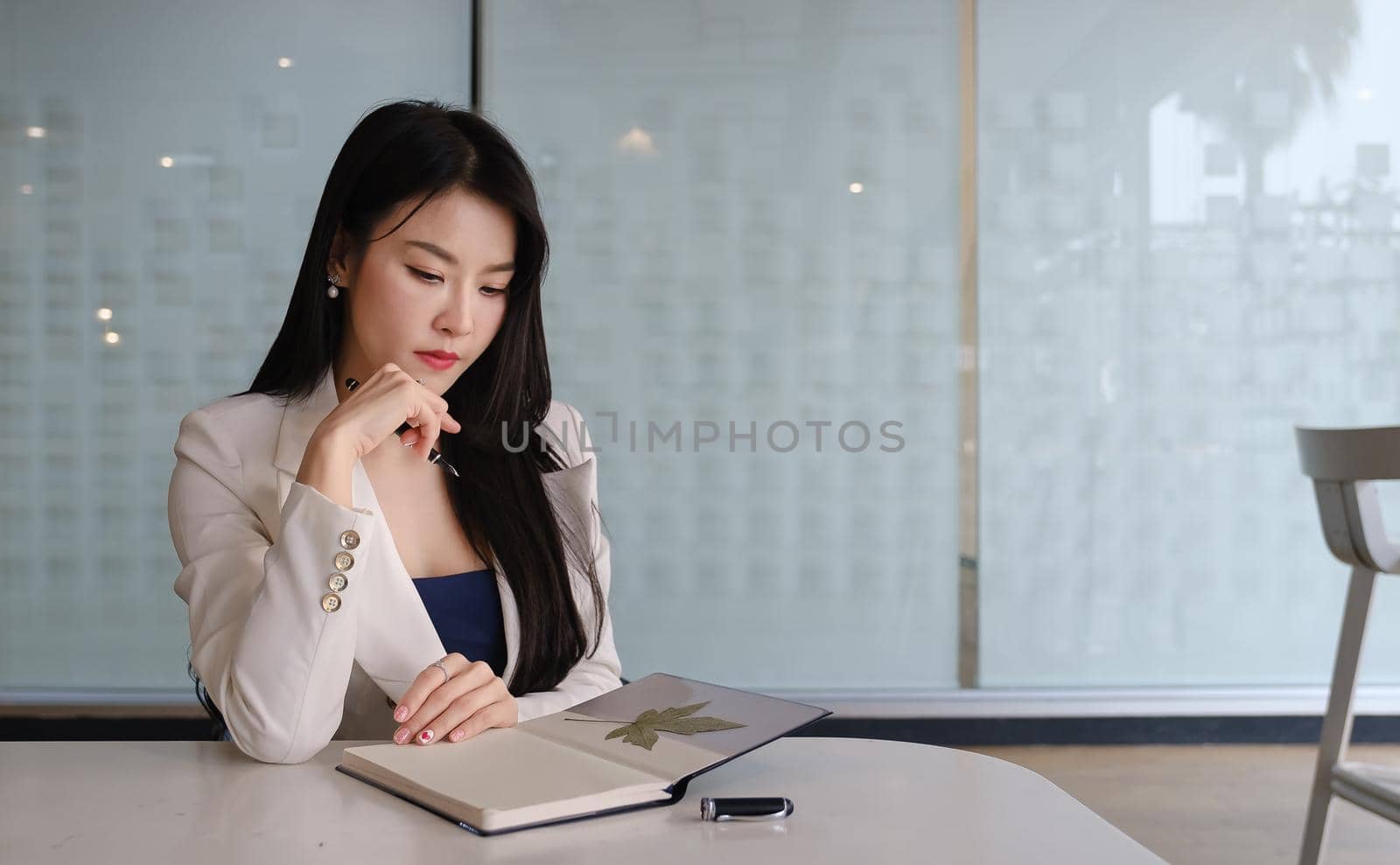 Businesswoman thinking about work with notebook at her office desk