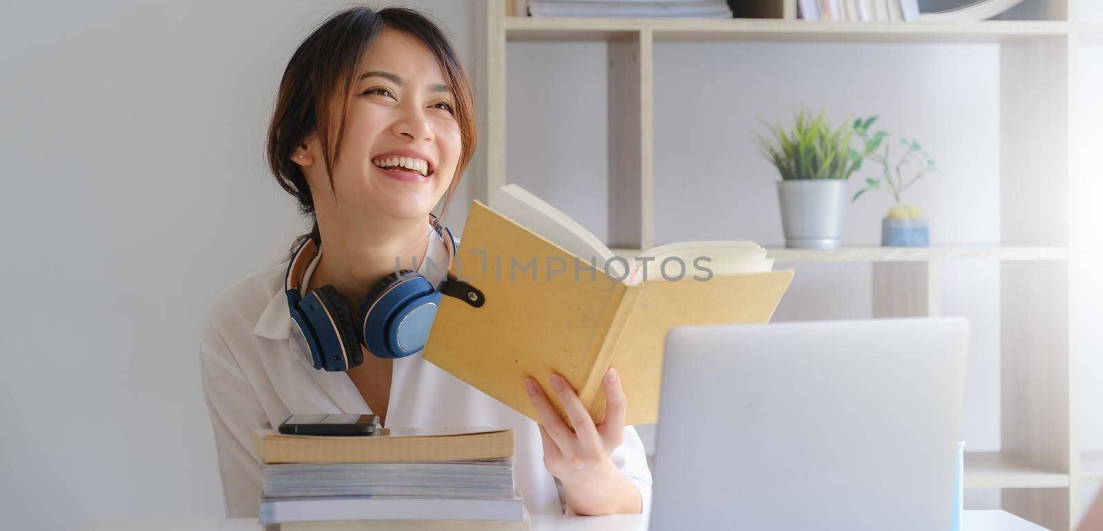 Portrait of smiling asian student girl and reading a book at homeschool before learning virtual internet online class. covid pandemic. by itchaznong