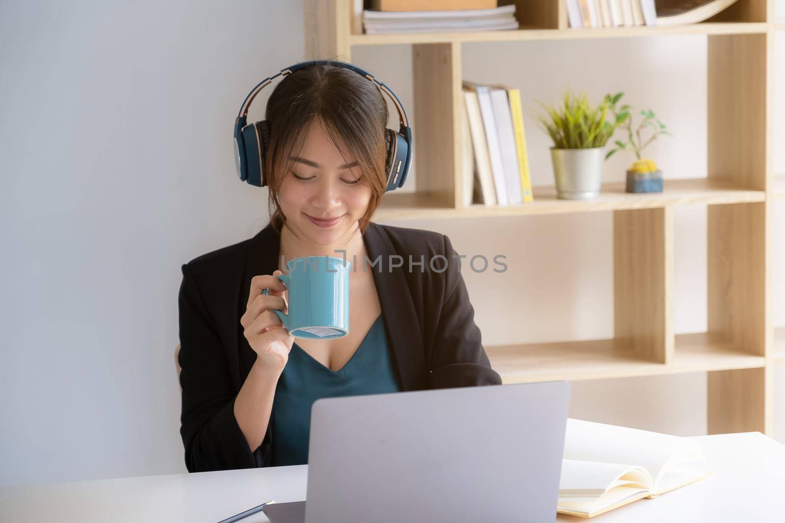 Portrait of smiling asian student girl and drinking coffee at homeschool before learning virtual internet online class. covid pandemic. by itchaznong