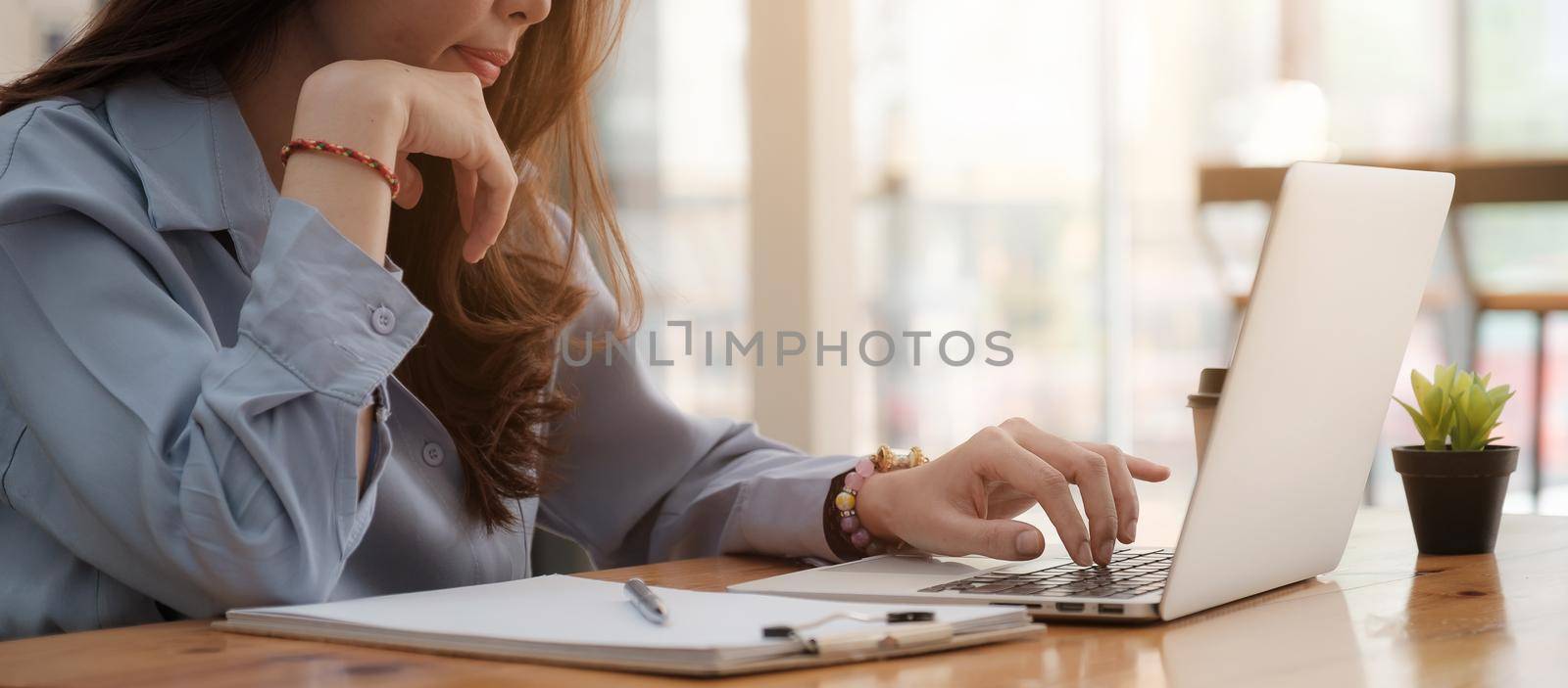 Closeup business woman using laptop and analyzing financial report, Work From Home concept. by itchaznong