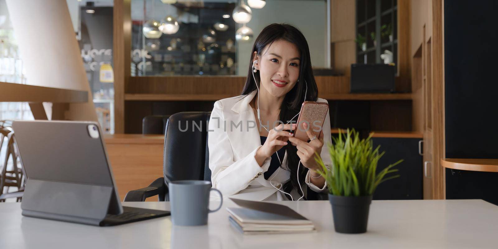Businesswoman using mobile phone with smile and sitting at her office desk for working