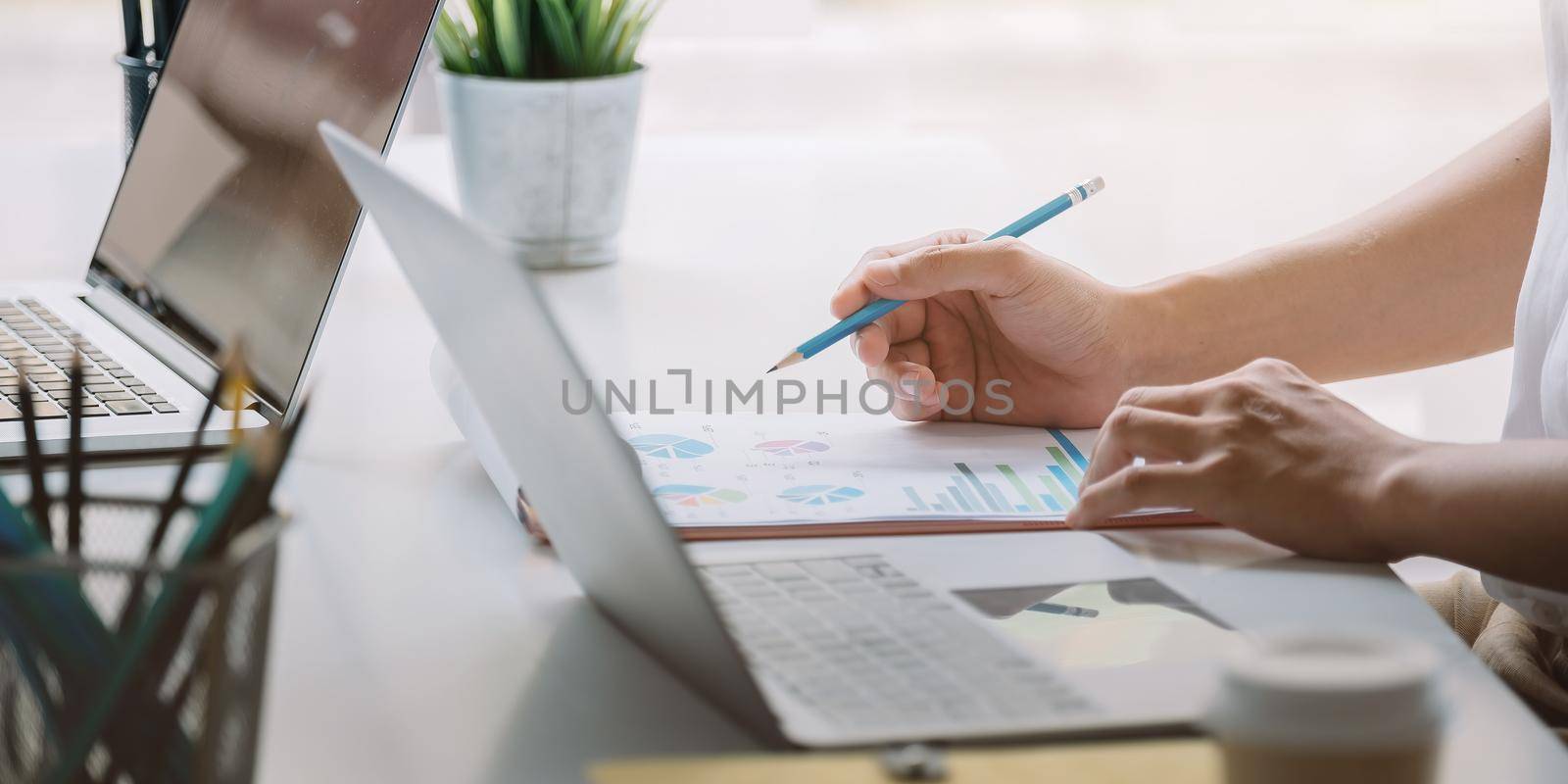 Close up Businessman hand holding pen and pointing at financial paperwork, financial charts to analyze profit concept.