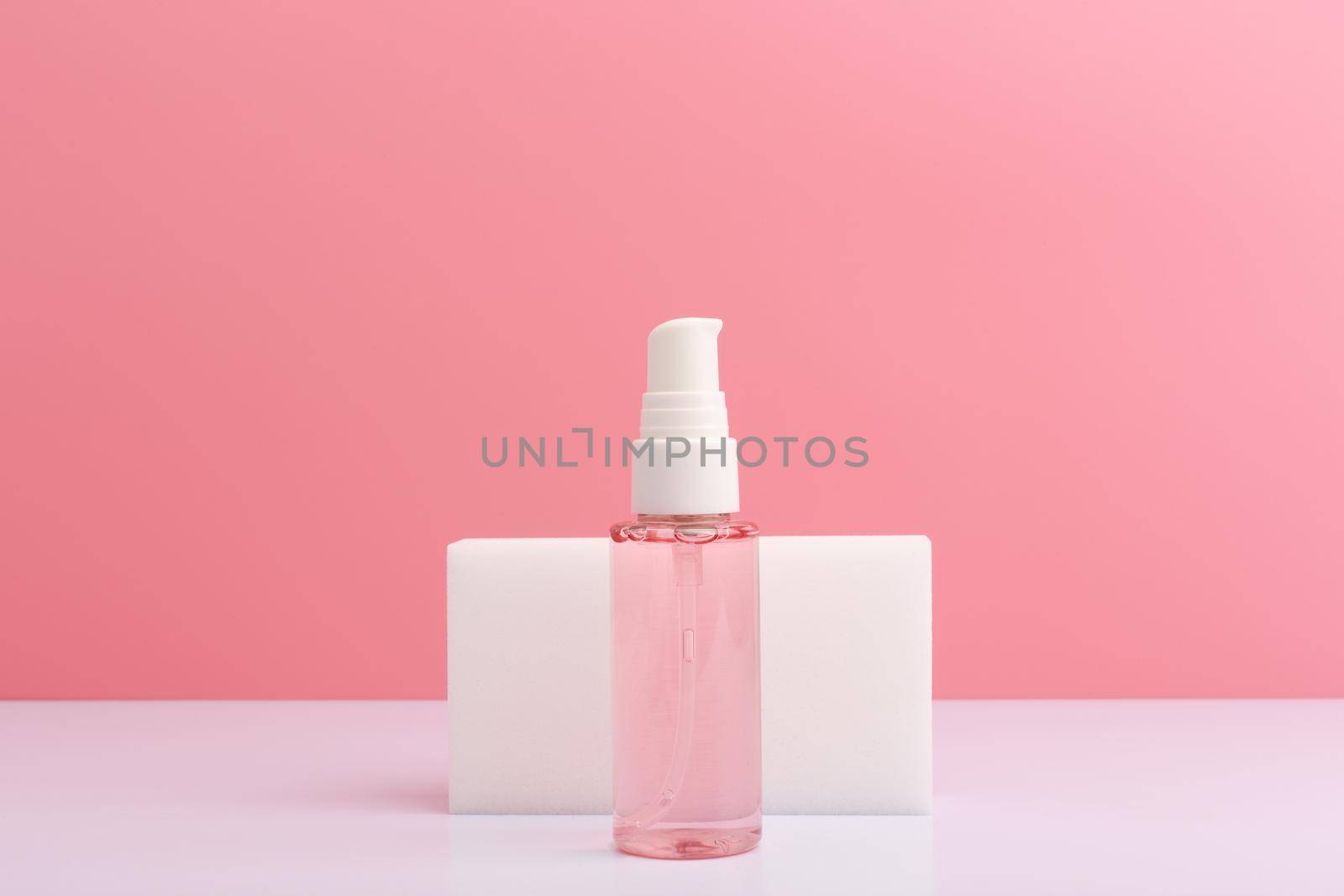 Cleansing and soothing foam or gel for face washing on white table against pink background with copy space. Concept of beauty products for daily skin care or anti acne treatment