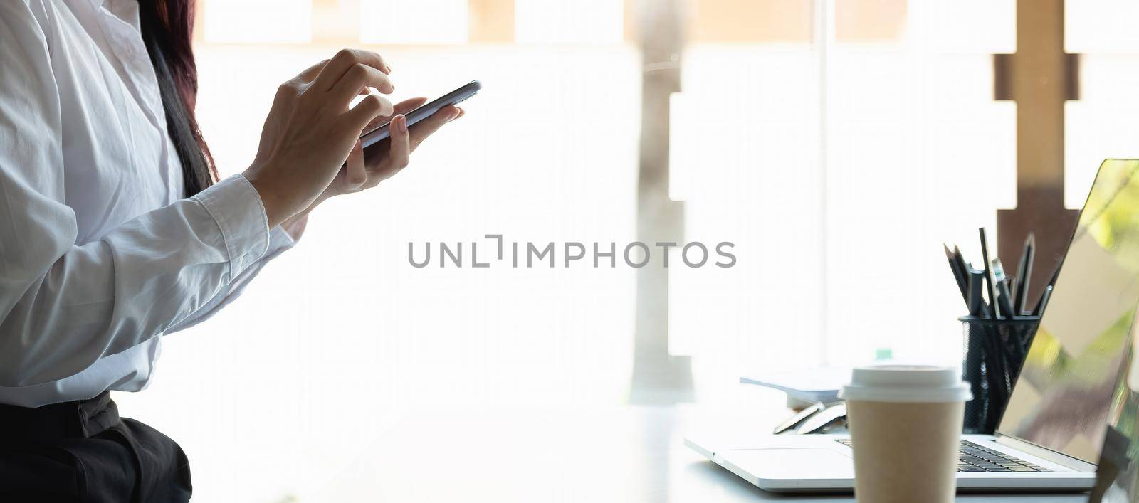 Shot of woman using smart phone at home office by nateemee