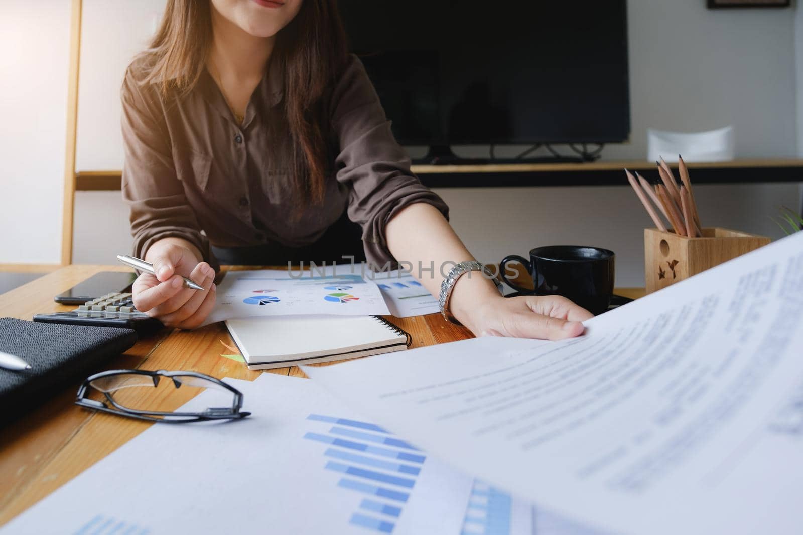 Close up Hand of Businesswoman pointing and analyzing charts by document