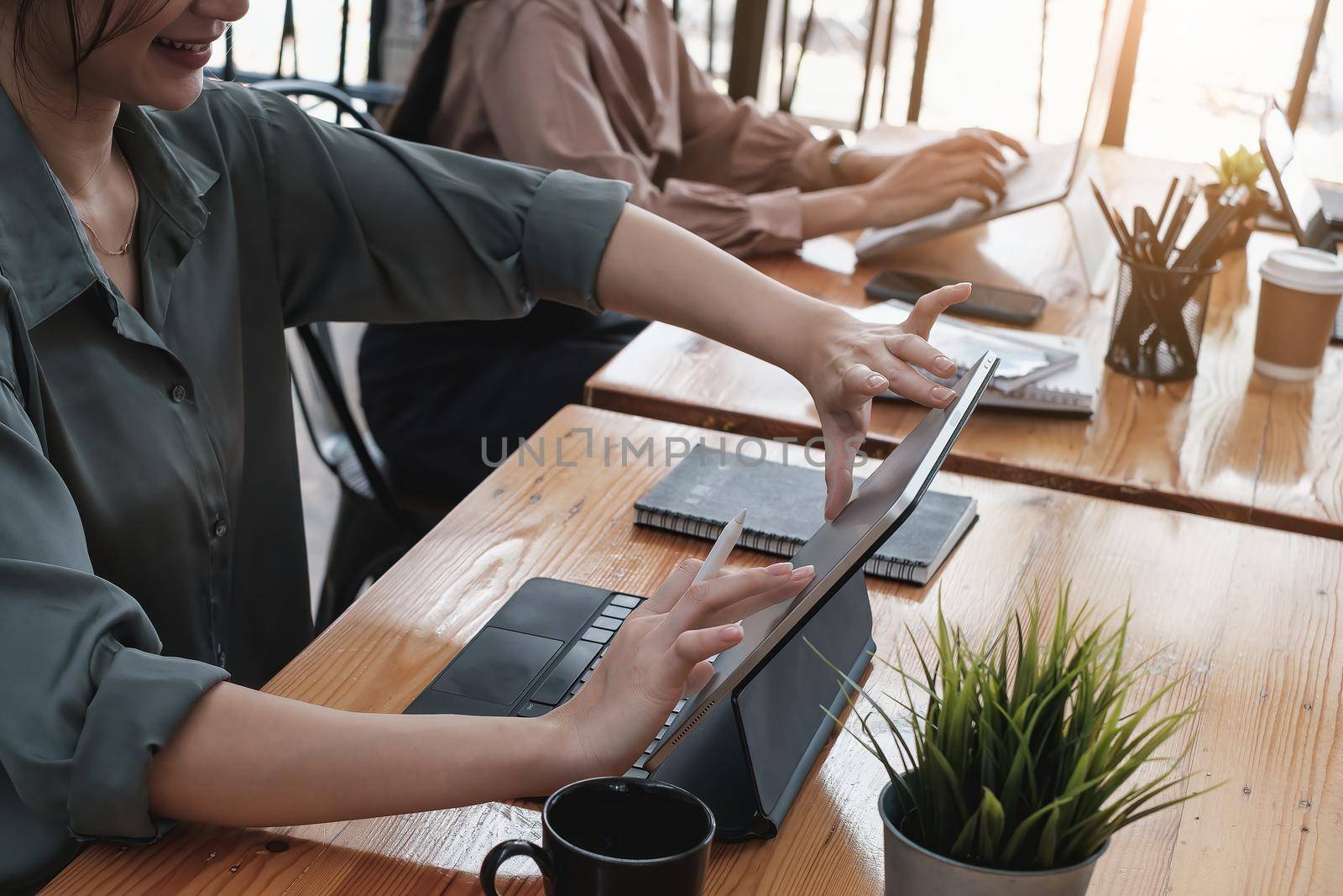 Young creative designer holding stylus pen and hand sketching on screen of digital tablet while sitting at home office, work from home concept