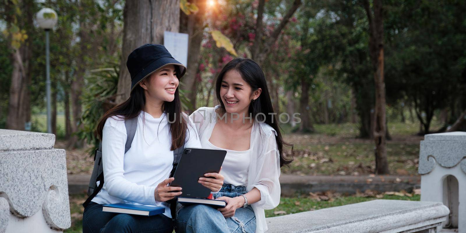 Asian woman traveler with backpack using maps on tablet and sitting in park, travel holiday relaxation concept. by itchaznong