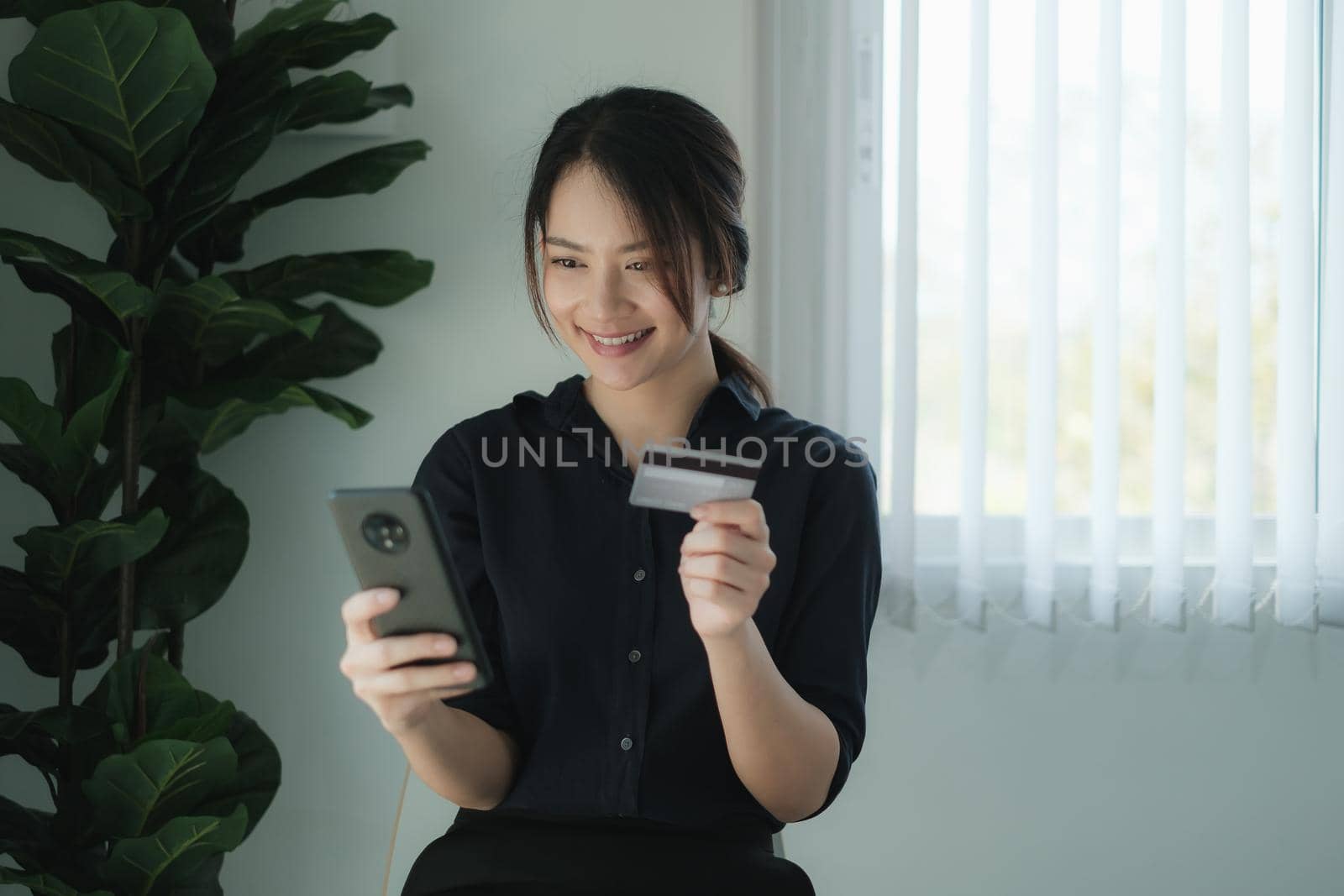 Mobile banking. Woman using online banking with credit card on mobile phone. Digital and internet payments shopping on network. by itchaznong