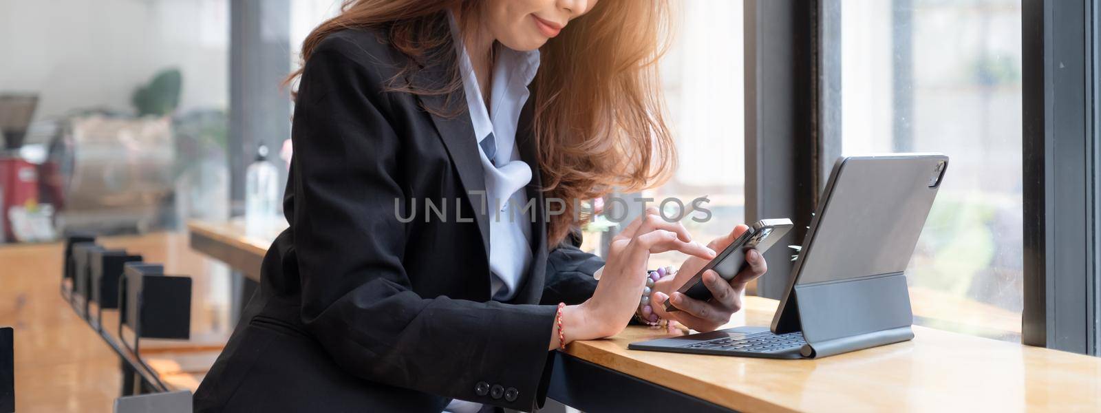 Businesswoman using mobile phone with smile and sitting at her office desk for working