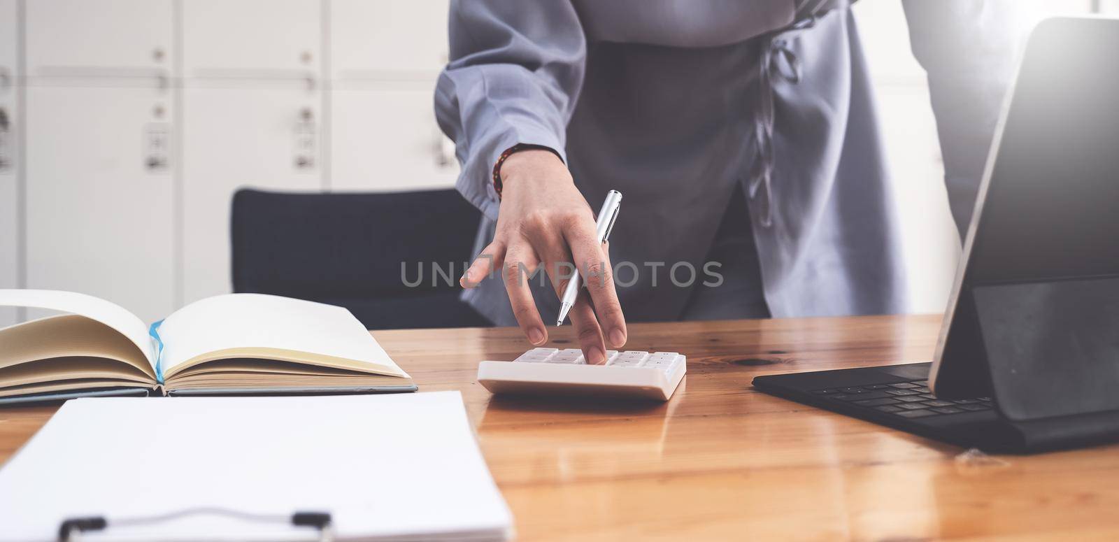 Accountant hand holding pen and using calculator to analyze sales growth in the global workplace market