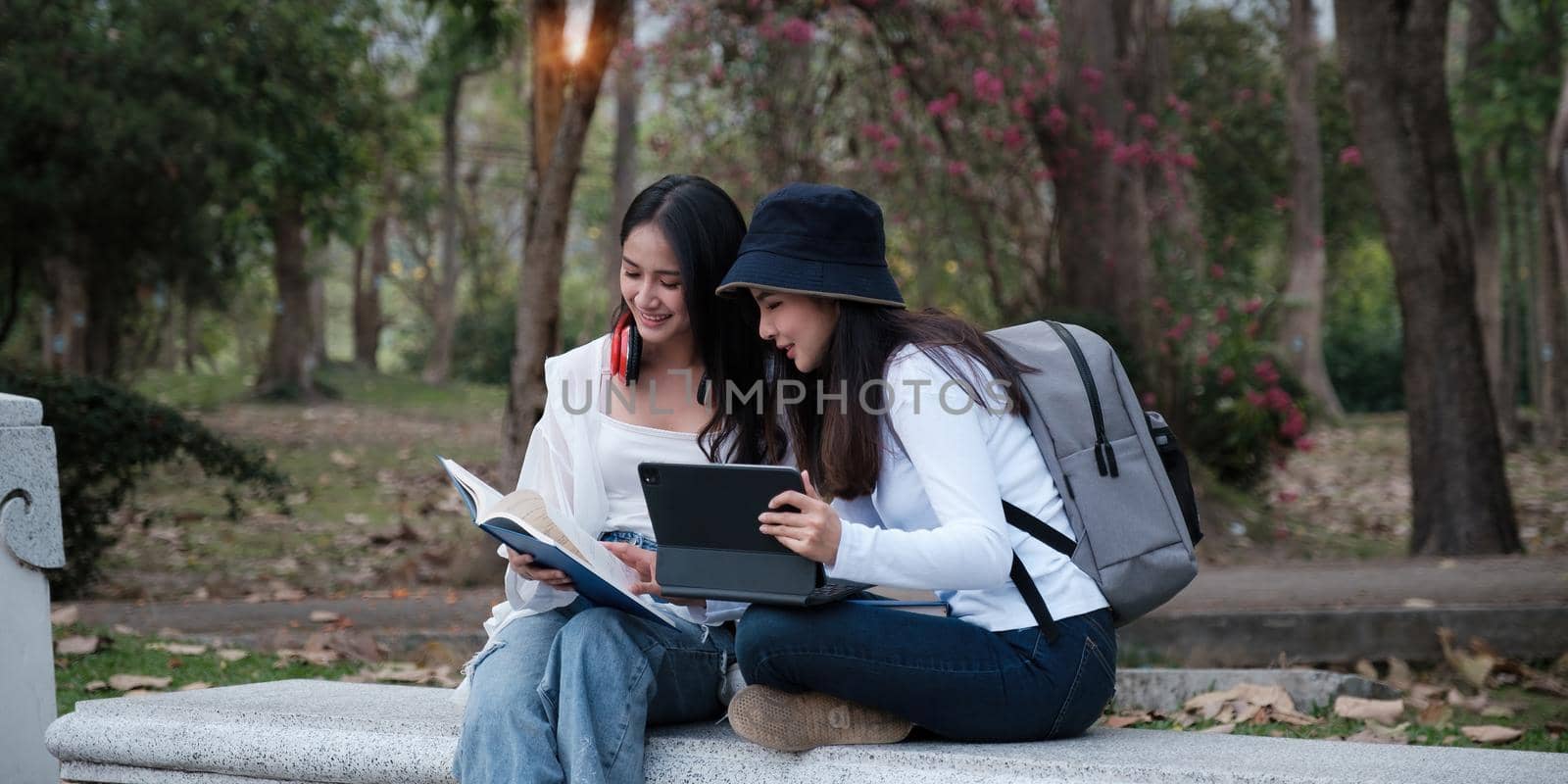 Asian woman traveler with backpack using maps on tablet and sitting in park, travel holiday relaxation concept. by itchaznong