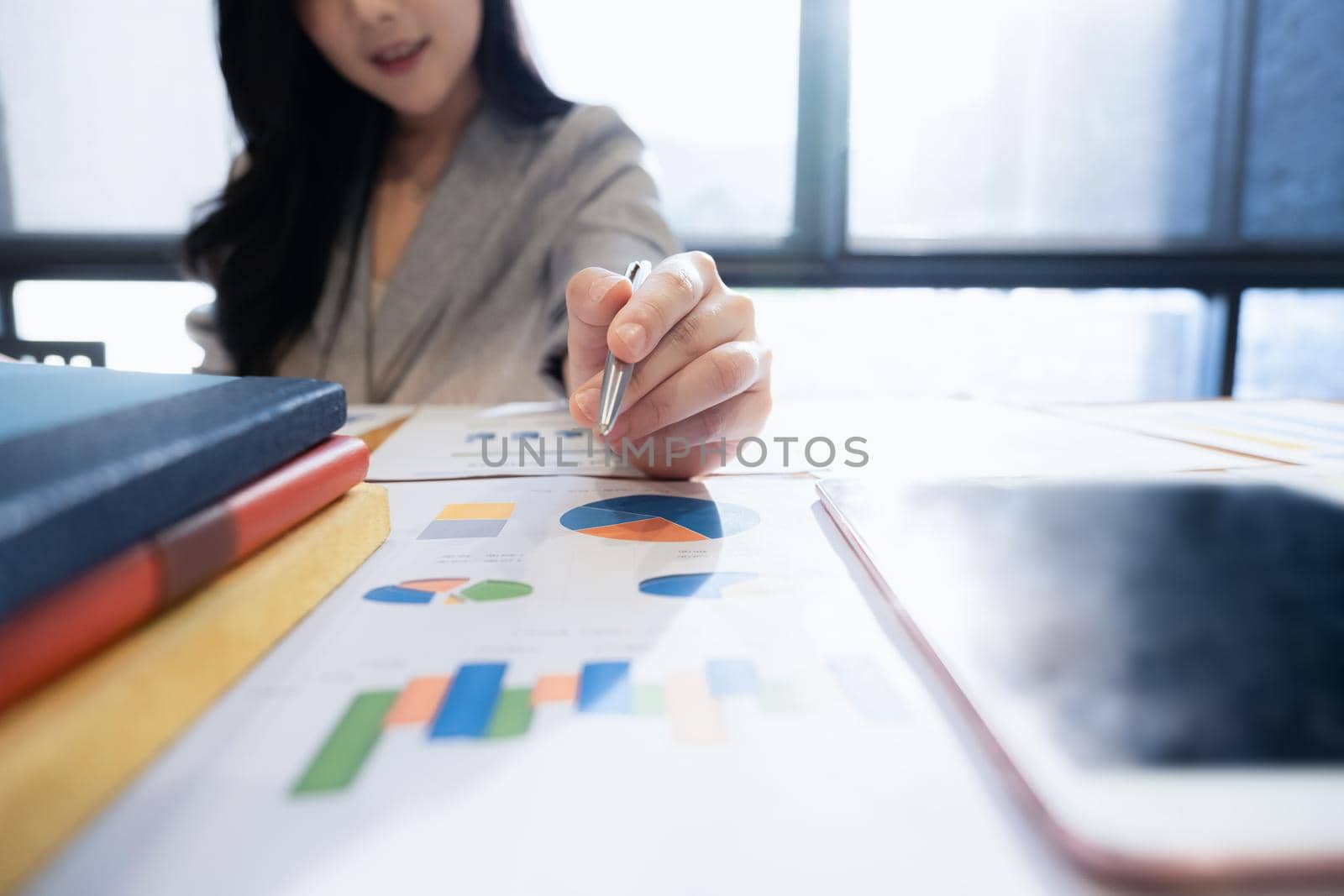 Close up Asian Businesswoman hand holding pen and pointing at financial paperwork