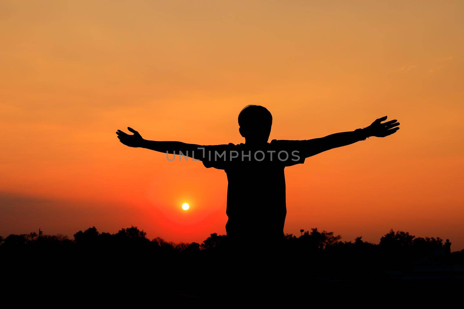Silhouette of male meditating and yoga practicing with exercise at sunrise in public park morning by pramot