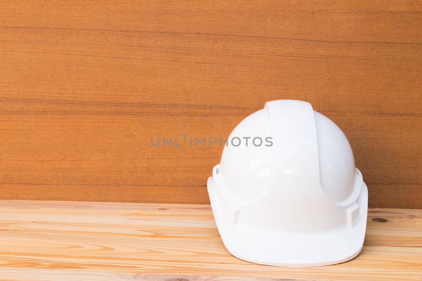 white safety helmet plastic construction of engineering on wood floor table background with copy space add text by pramot