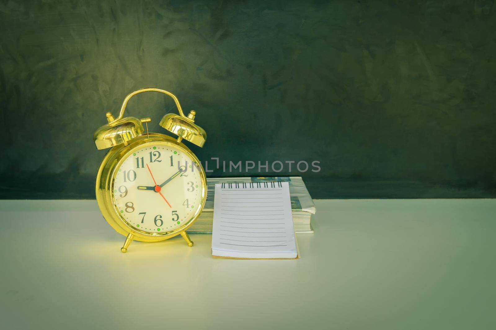 alarm clock old vintage gold and book over white on black background. with copy space add text color cinematic Style tone