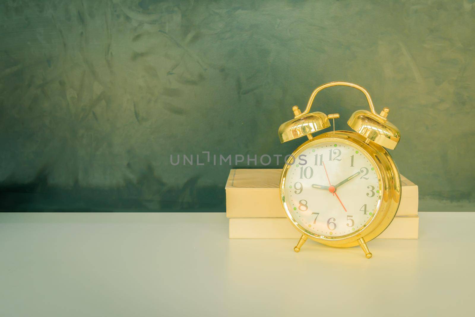 alarm clock old vintage gold and book over white on black background. with copy space add text. color cinematic Vintage style tone