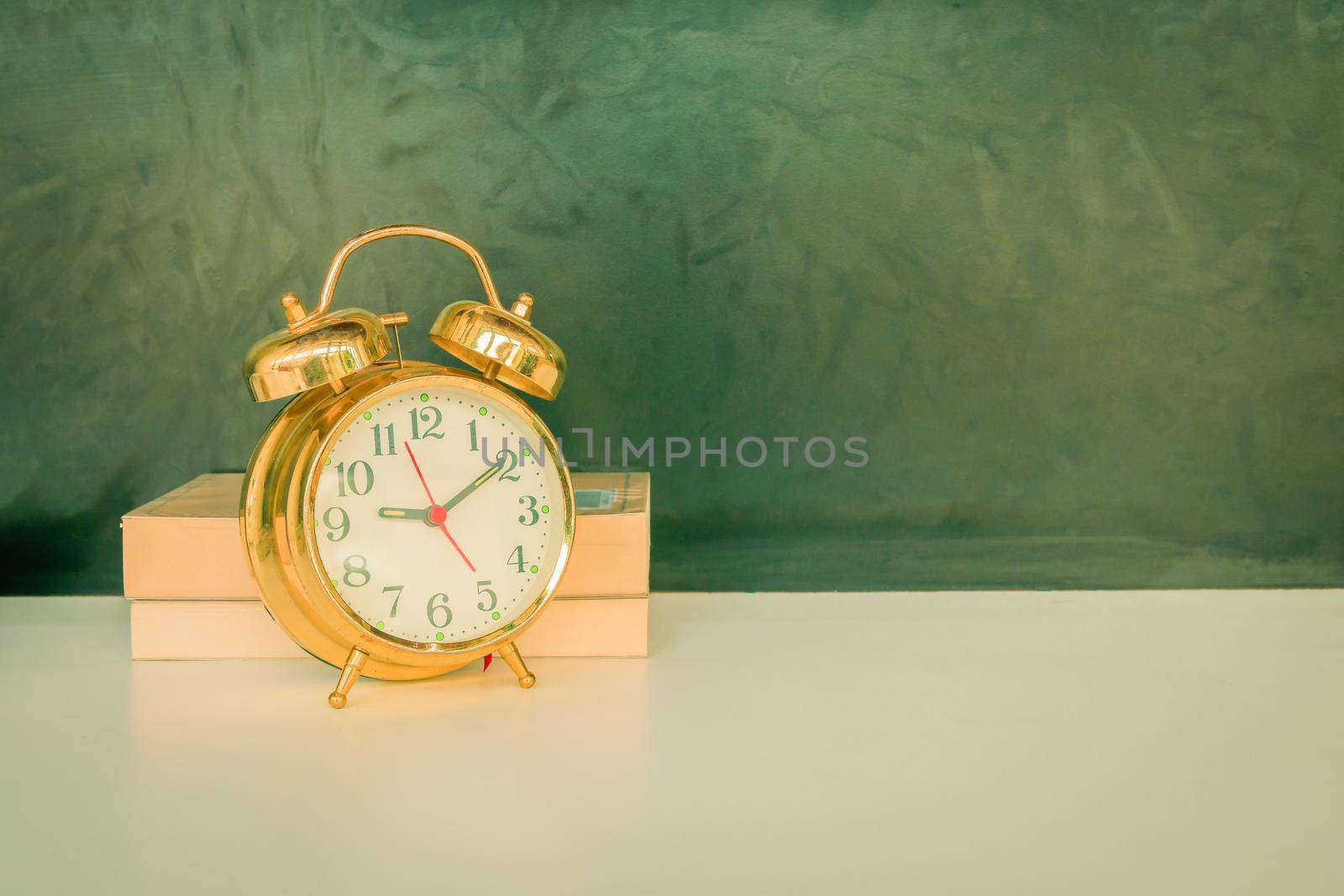 alarm clock old vintage gold and book over white on black background. with copy space add text. color cinematic Vintage style tone